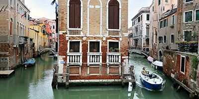 A brown stone building in the middle of the Venice canals.