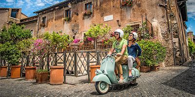 Two people riding on a vespa in Rome, Italy
