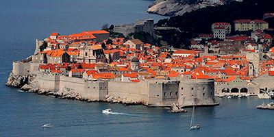 Dubrovnik from the water with a wall around the red roofed buildings.