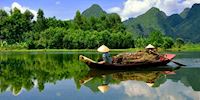 Two Mekong boatmen paddle down the river along the lush forest