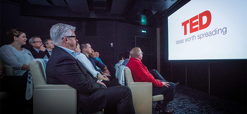 Guests watching a TED Talk on a display