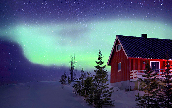 A red house in Tromso, Norway with the Aurora Borealis in the sky