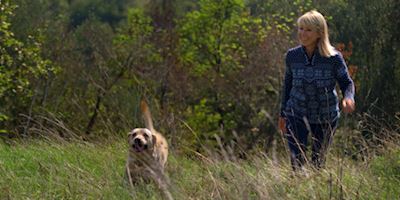 Karine Hagen and her dog, Finse, walking through a field.